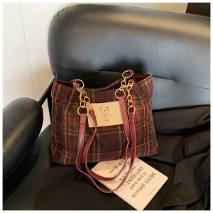 Detail of vintage plaid tote bag with cute bear leather patch and golden chain straps