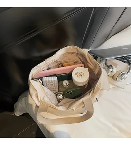 Macro view of spacious interior of cream canvas tote bag with laptop and pockets