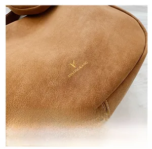 Detailed macro shot of brown leather texture and gold logo on French retro crossbody bag