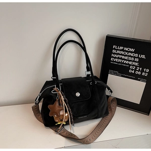 Detail of black nylon tote with silver buckle, bear charm, and patterned strap