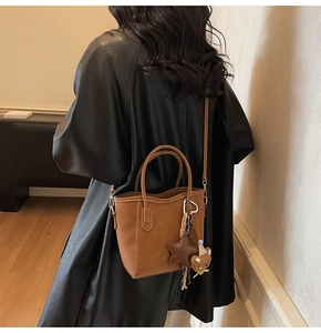 Mini sac seau marron avec breloque d'ours vu sous un angle élevé depuis l'arrière