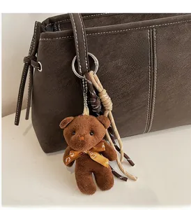 Detail of dark brown lychee grain tote bag with white stitching and bear charm