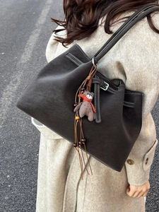 Deep brown matte tote bag with white contrast stitching and a cute bear charm pendant