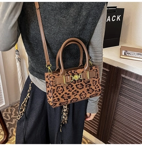 Detail of leopard print crossbody bag with brown leather handles and golden metal buckle