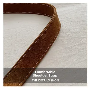 Detail of a brown leather shoulder strap with visible stitching and lychee grain texture
