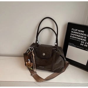 Detail of dark brown retro tote bag with ethnic woven strap and cute bear charm