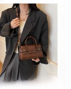 Dettaglio di una borsa a tracolla vintage in pelle opaca marrone con fibbia e cinturino