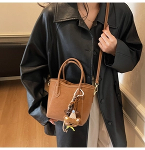 Détail du sac seau en cuir marron avec pendentif ours et bandoulière réglable chic
