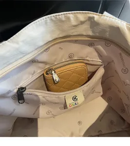 Macro shot of large tote bag interior with monogram lining and zippered pocket storage