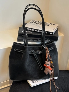 Black vintage leather tote bag with white stitching and cute bear charm on books