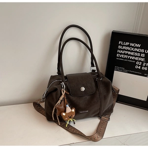 Detail of dark brown matte leather tote bag with stylish patterned fabric shoulder strap