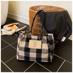 Close-up of houndstooth wool tote bag with leather straps and bear logo detail