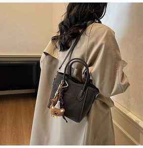 Vue détaillée du sac seau mat avec surpiqûres blanches et pendentif ours en peluche