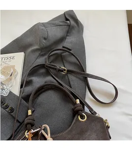 Close-up of brown suede bucket bag with gold hardware and stylish knot details