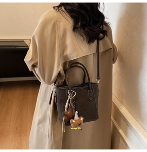 Détail du sac seau marron mat avec coutures blanches et breloque ours mignonne