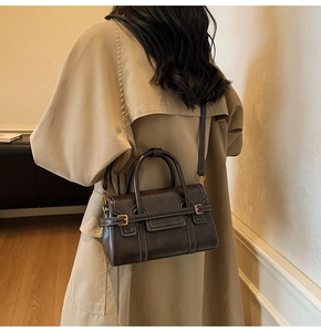 Dettaglio di borsa vintage in pelle marrone con cuciture a contrasto e fibbie dorate