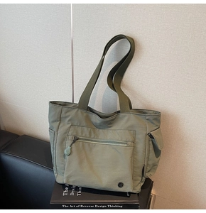Detail of army green nylon tote bag showing multiple functional zipper pockets and straps