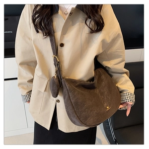 Detail of dark brown suede crescent crossbody bag with mini coin purse on beige coat
