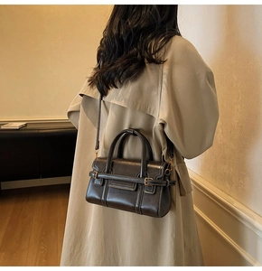 Dettaglio macro di borsa vintage in pelle marrone scuro con cinturino a fibbia e tracolla
