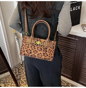 Close-up of leopard print crossbody bag with golden heart buckle and brown handles