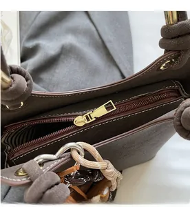 Close-up of smooth gold zipper and brown suede material on a stylish women's handbag