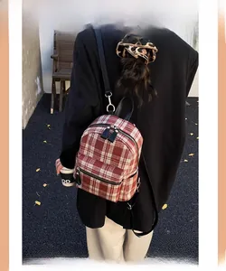 Detail of red and white plaid tweed backpack with black leather straps on a model