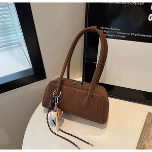 Detail of brown suede shoulder bag with MUHET SHI SHANG logo and baseball charm
