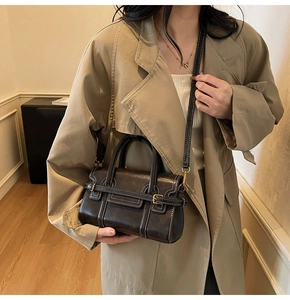 Dettaglio di piccola borsa quadrata marrone vintage con cuciture bianche e manico