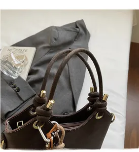 Detail of vintage coffee leather handbag featuring knot handle and gold hardware