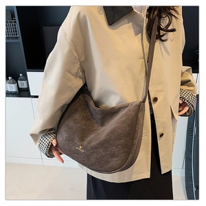 Detailed view of the dark brown suede hobo bag featuring gold metal logo and zipper