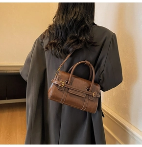 Dettaglio della borsa vintage in pelle marrone scuro con fibbie dorate e tracolla regolabile
