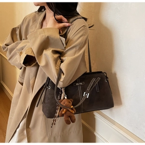 Detail of vintage brown suede shoulder bag with contrast stitching and bear charm