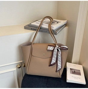 Close-up of beige litchi grain leather tote bag featuring elegant H-pattern silk scarf