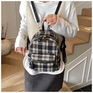 Detail view of plaid tweed backpack with black leather straps on a female model