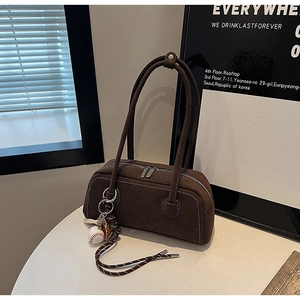 Detail of dark brown suede boston bag with white contrast stitching and baseball charm