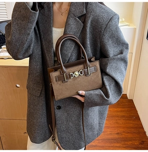 Detail of vintage brown patchwork handbag with gold metal buckle and dual handles
