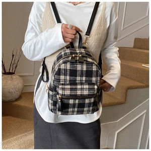 Detail of black and white plaid tweed mini backpack with gold zippers and leather straps