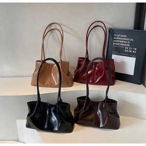 Close-up of four pleated leather tote bags in camel, burgundy, black, and brown colors