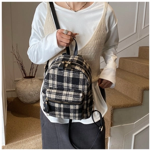 Detailed close-up of a black and white plaid backpack with premium leather handle strap