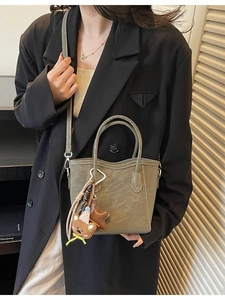 Sac seau élégant vert olive mat avec breloque ours, porté par un mannequin femme