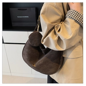 Detail of dark brown suede half-moon bag with gold logo and round coin purse accessory