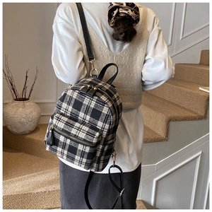 Plaid pattern tweed backpack for women styled on person in a cozy interior setting
