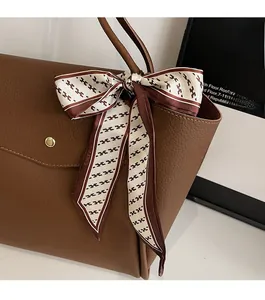 Gros plan d'un sac cabas en cuir litchi marron avec foulard décoratif à motif H sur l'anse