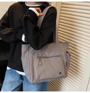 Detailed close-up of a grey nylon multi-pocket tote bag with wide shoulder strap