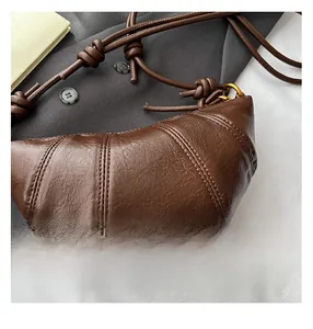 Detail of brown leather croissant bag with fine lychee texture and knotted shoulder strap