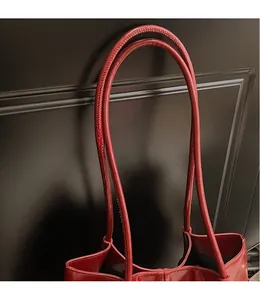 Detail of dark red glossy leather tote bag featuring long slim shoulder straps for daily use