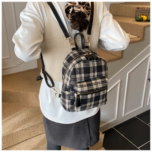 Detail of classic plaid tweed backpack featuring black and white texture and golden zippers