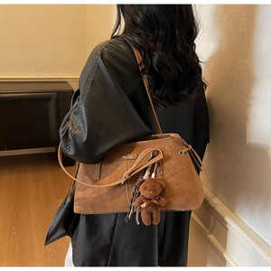 Detail of vintage brown suede tote bag with cute bear charm and drawstring closure