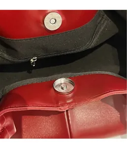 Detailed close-up of a silver magnetic snap closure on a red leather tote bag with stitching