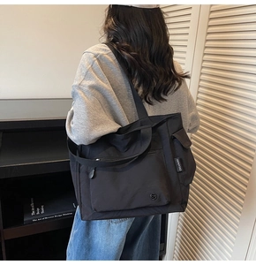Detail view of black canvas tote bag with multi-pocket design and CHUANGMI side label